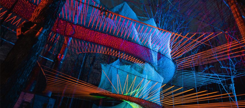 A treetop ropes course in a forest setting at night